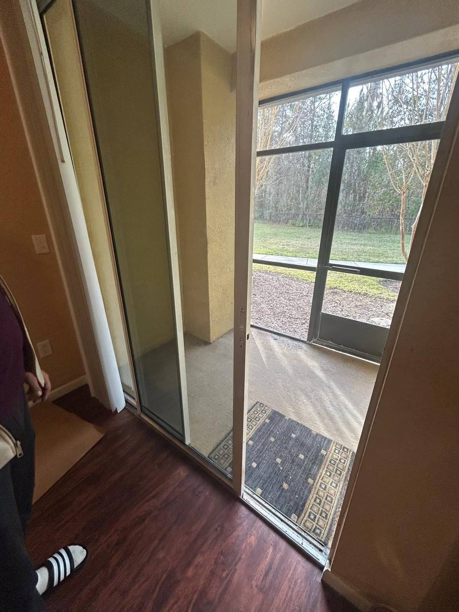 Technician adjusting a sliding door frame and screened porch entry on site