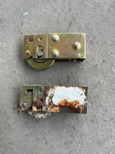 New roller next to a heavily corroded roller, a common cause of a door jumping its track